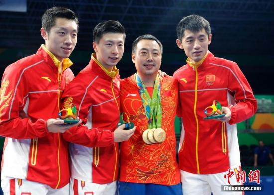当地时间8月17日，2016里约奥运男子乒乓球团体赛决赛举行，中国队最终以总比分3：1的成绩战胜日本队获得冠军。图为许昕(左一)、马龙(左二)、刘国梁(右二)、张继科在领奖台上合影。/p中新网记者 盛佳鹏 摄